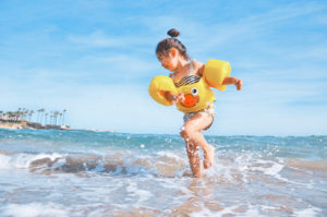 Little girl running around at the beach and splashing in the waves